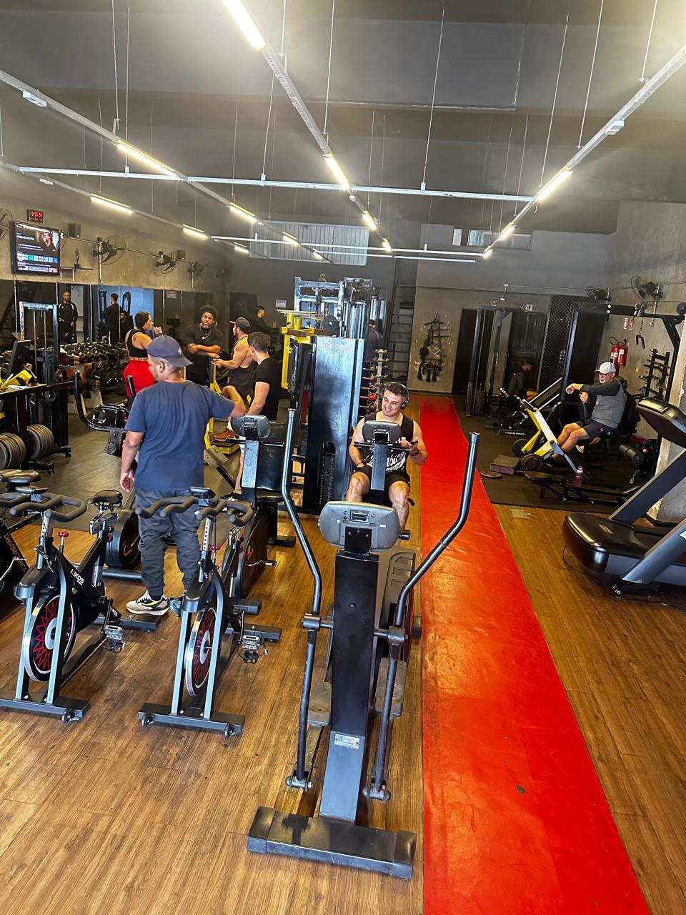 Área de cardio da Academia Status, com esteiras, bikes e alunos treinando